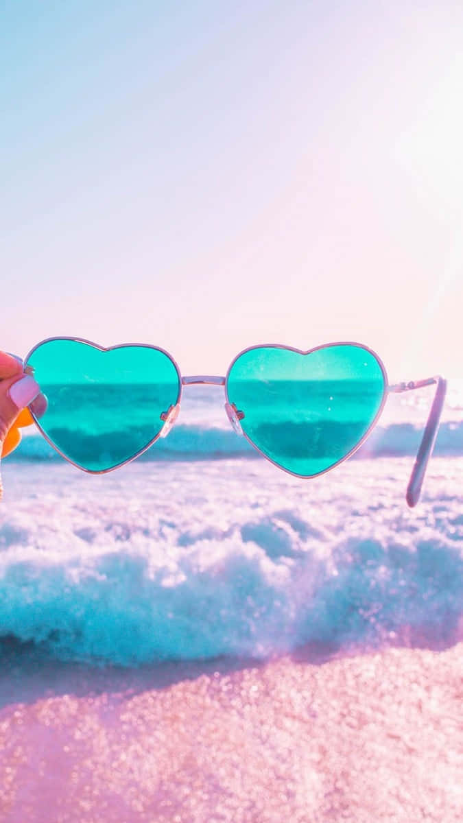 Einefrau Hält Ein Paar Herzförmige Sonnenbrillen Am Strand.