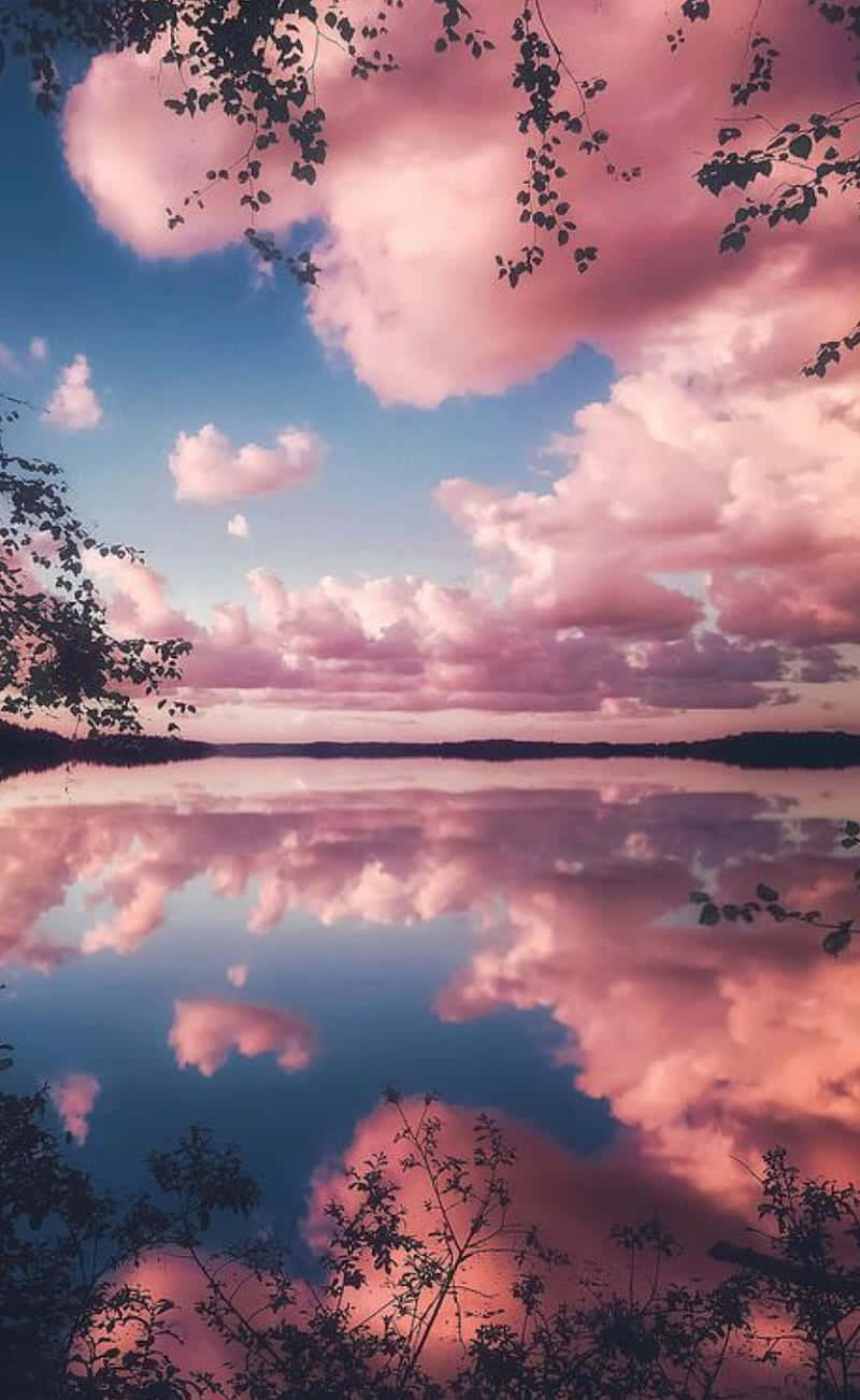 En pink himmel med skyer spejlet i vandet