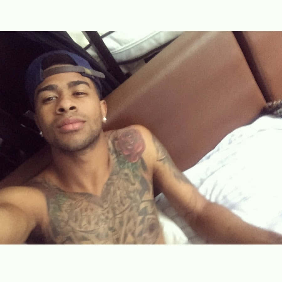 A Man With Tattoos Laying On A Bed Wallpaper