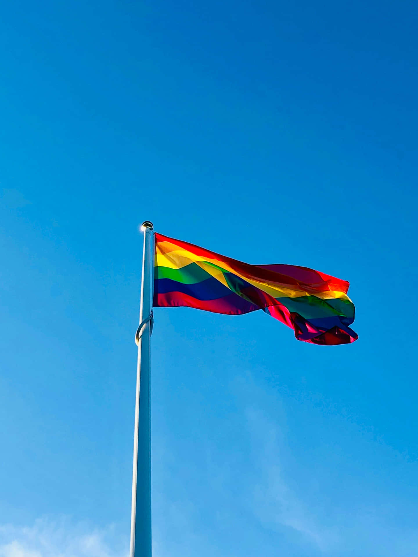 Pride Flag Waving Against Blue Sky Wallpaper
