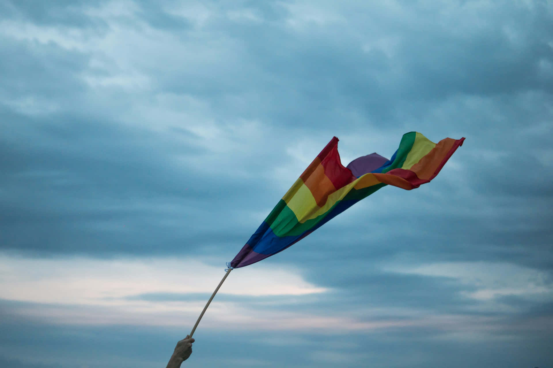 Pride_ Flag_ Waving_ Against_ Cloudy_ Sky Wallpaper
