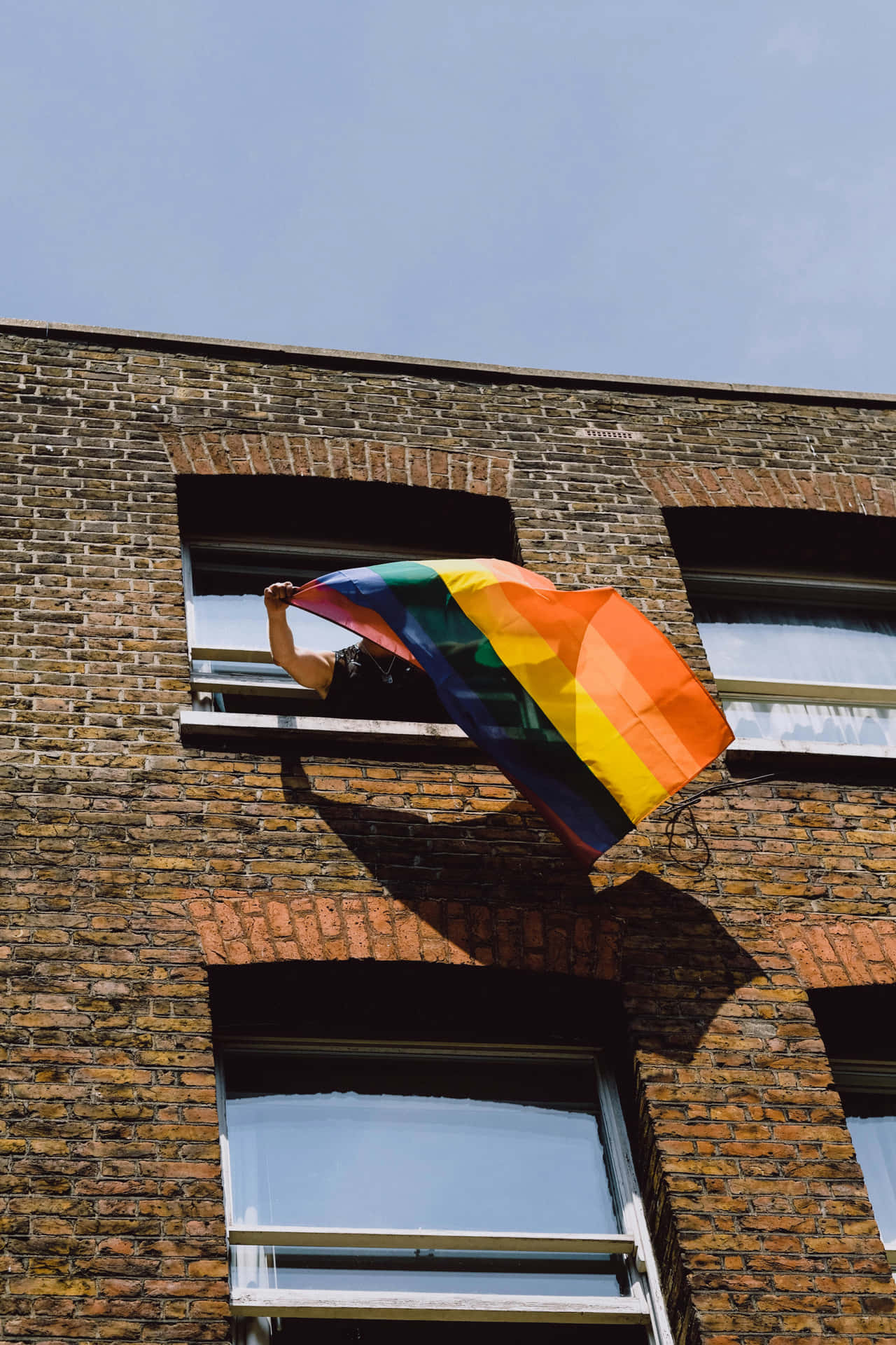 Pride_ Flag_ Waving_from_ Window Wallpaper