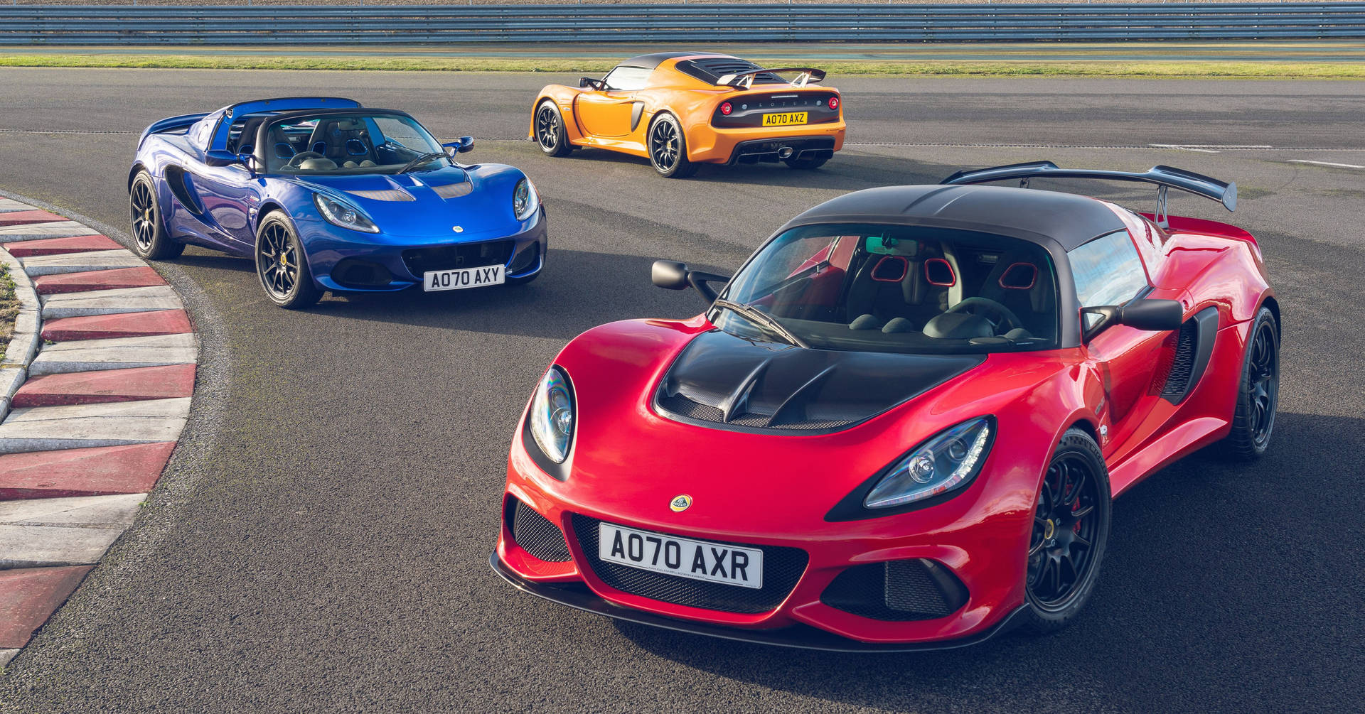 Primære farvede Lotus Exige-biler suser over skærmen Wallpaper
