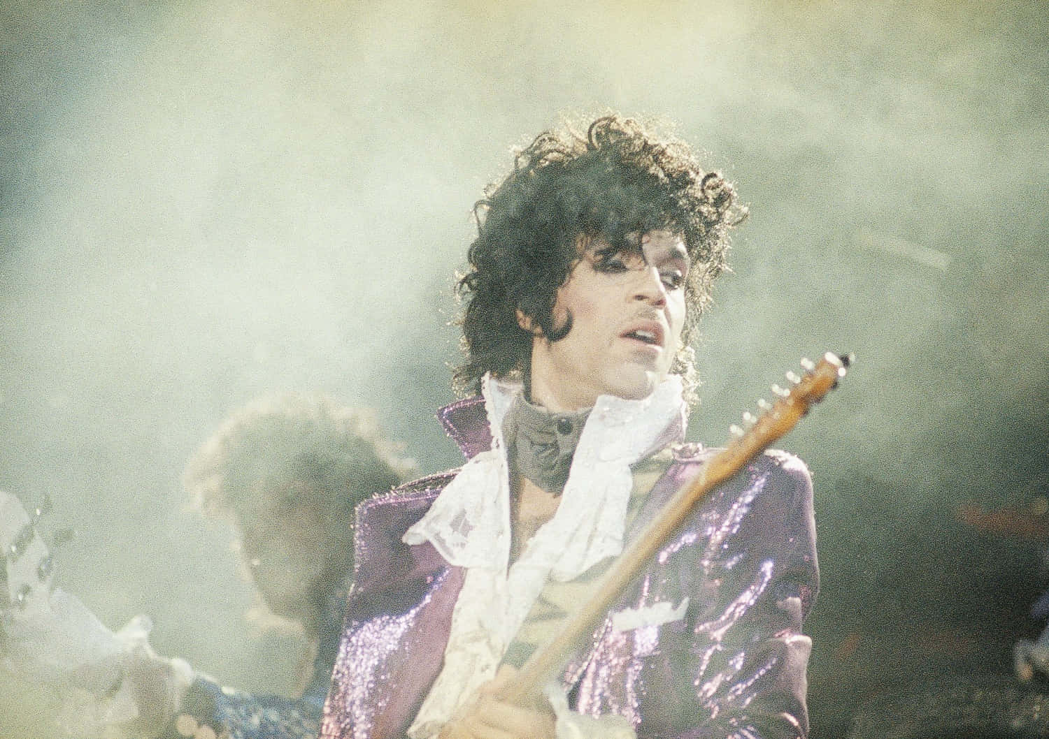 Prince stands onstage in all purple.