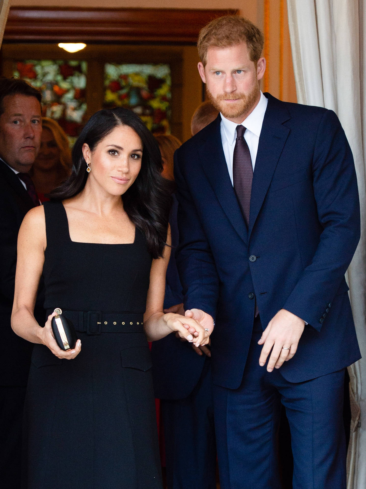 "Prince Harry in a thoughtful moment with Meghan Markle in the background." Wallpaper