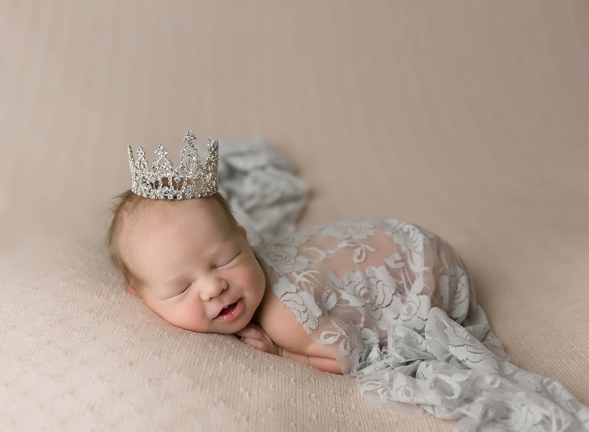 A Baby Girl Wearing A Tiara While Laying On A Blanket Wallpaper