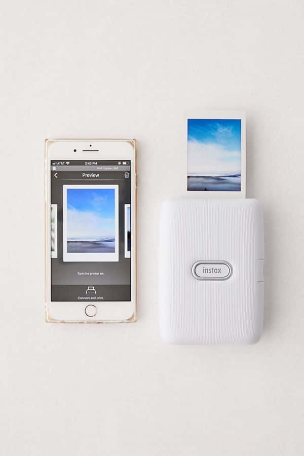 A White Polaroid Instant Print Machine Next To A Phone Wallpaper