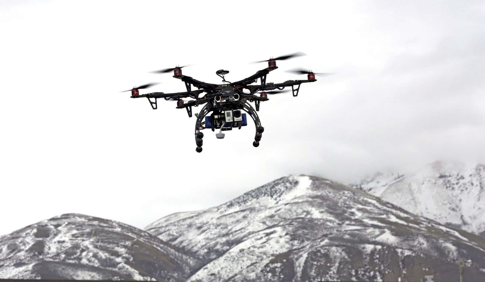 Professional Drone In Flight Mountain Backdrop Wallpaper