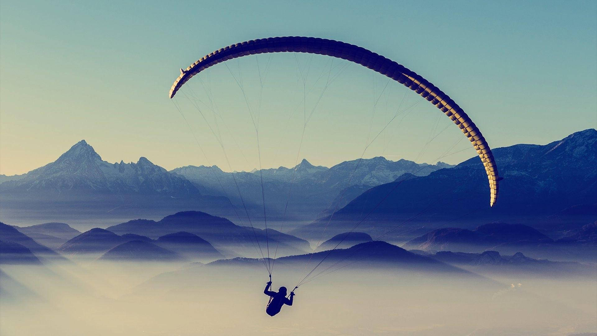 Professionel parasailing over et bjergområde Wallpaper