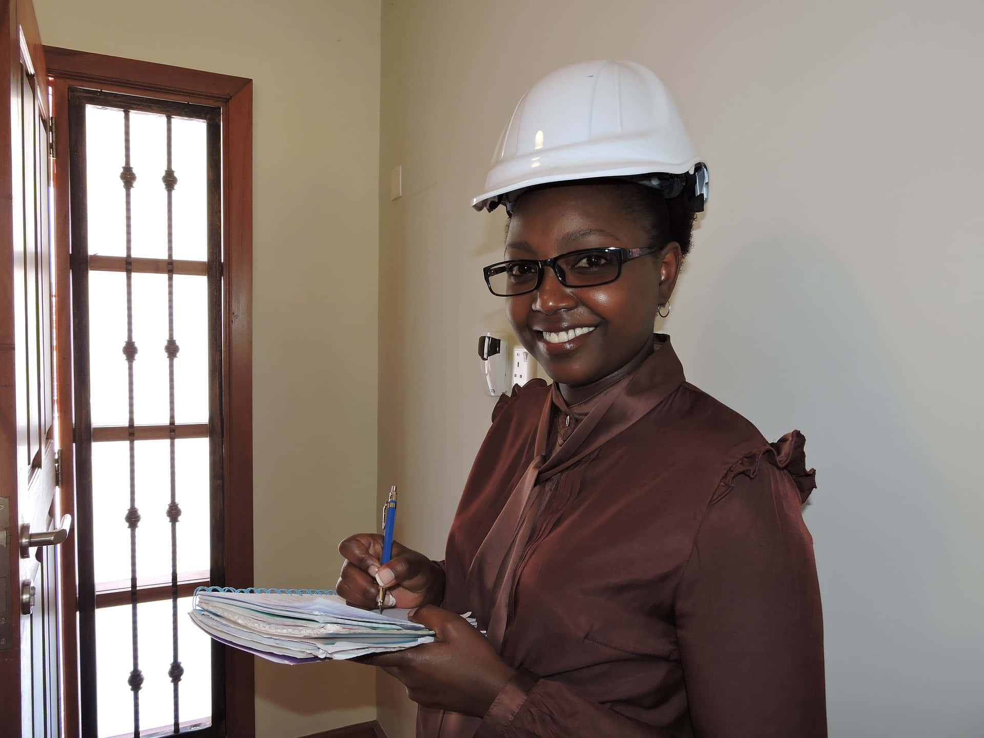 A Woman In A Hard Hat Holding A Notebook