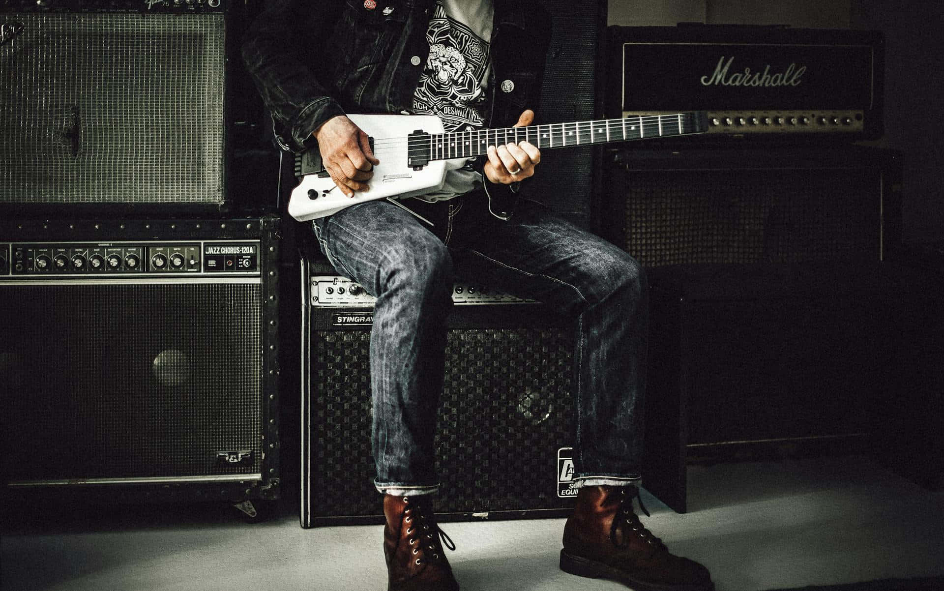 Punk Guitarist Amidst Amplifiers.jpg Wallpaper