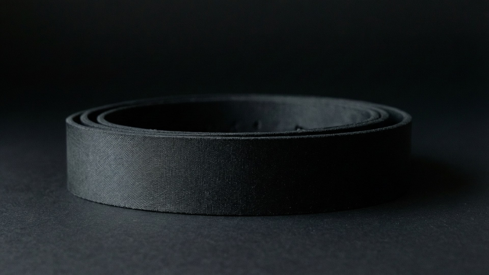 En minimalistisk baggrund af et sort bælte på sort baggrund.
