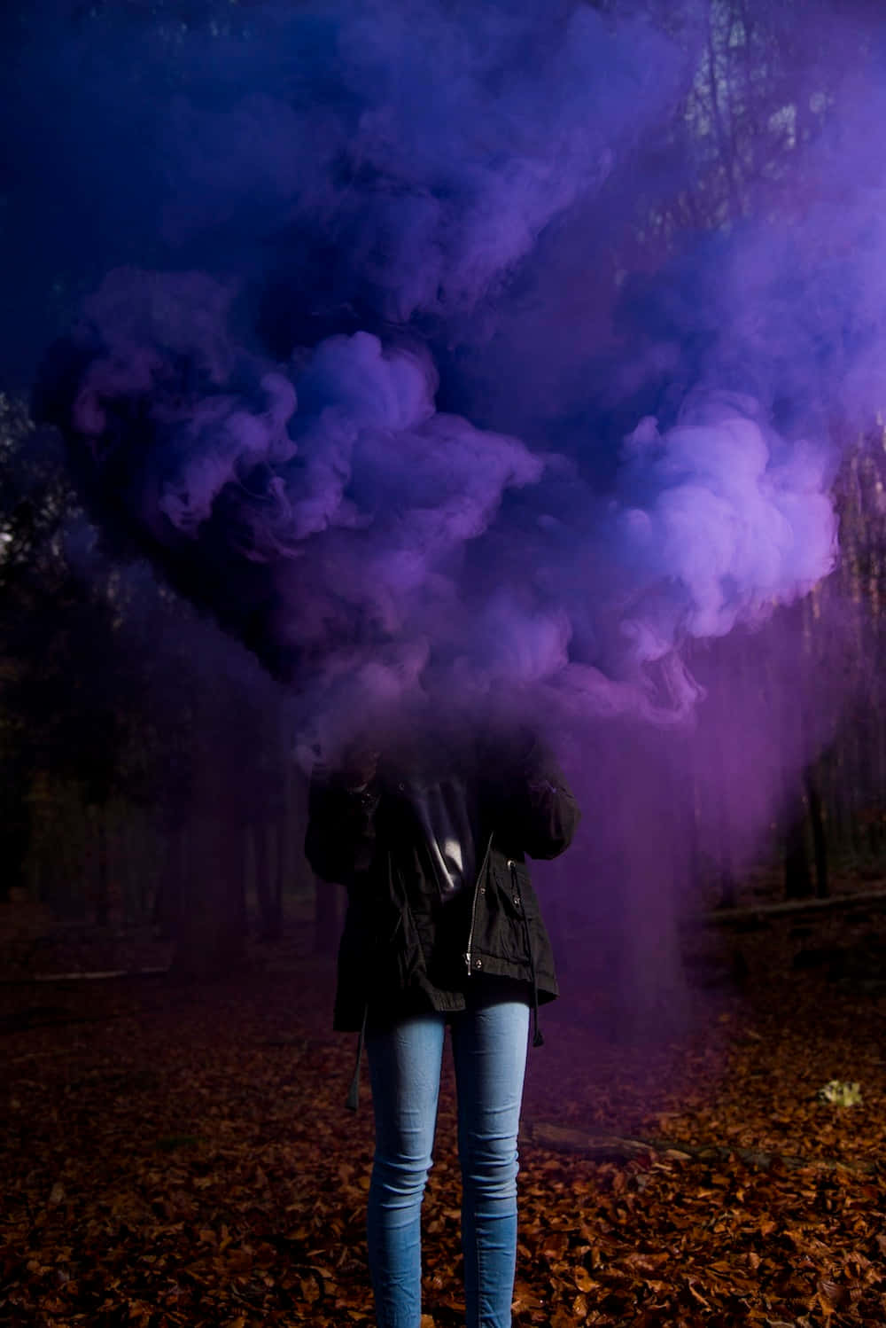 A Person Standing In The Woods With Purple Smoke
