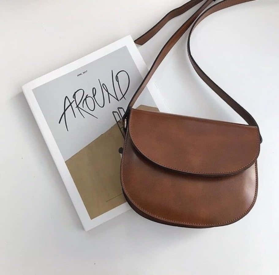 A Brown Leather Bag With A Book On Top