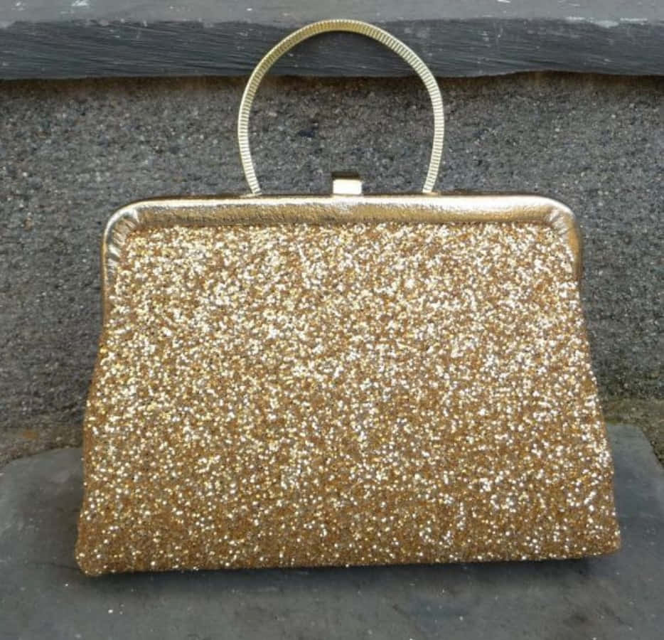 a gold glitter purse sitting on a stone wall