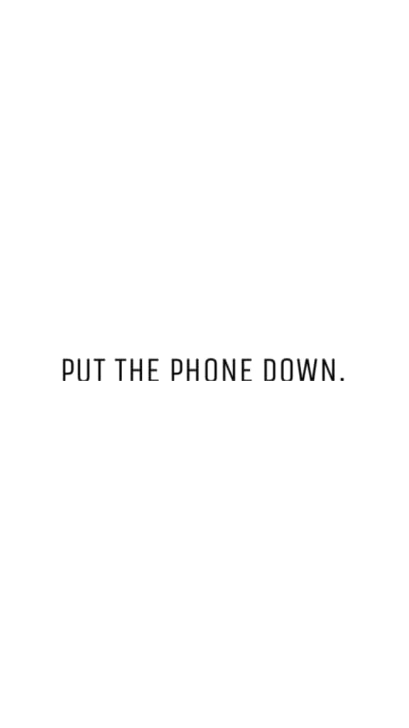 Et sort-hvidt foto af en telefon med ordene 'Læg telefonen væk' på det. Wallpaper