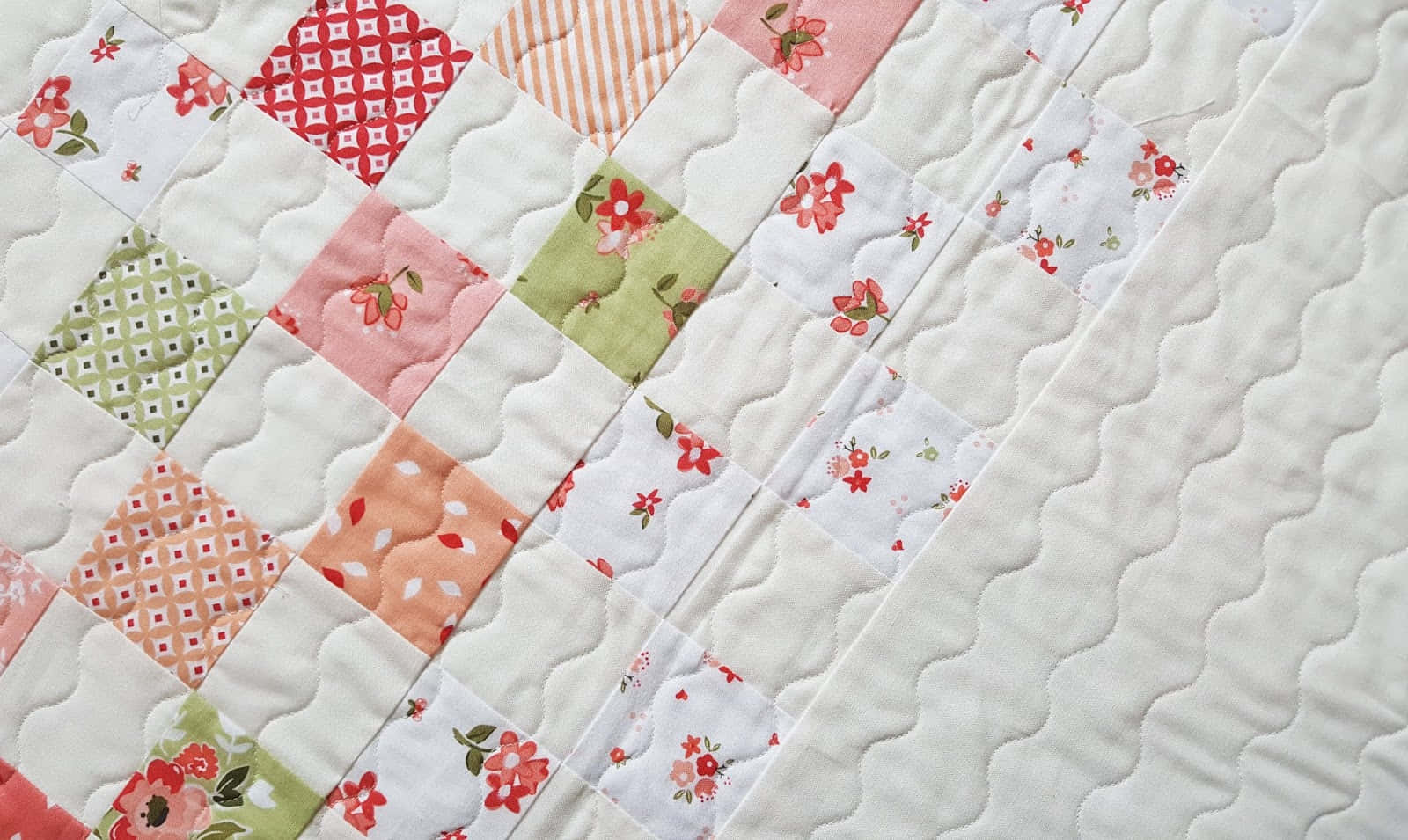 En quilt med et patcheremønster og blomster Wallpaper