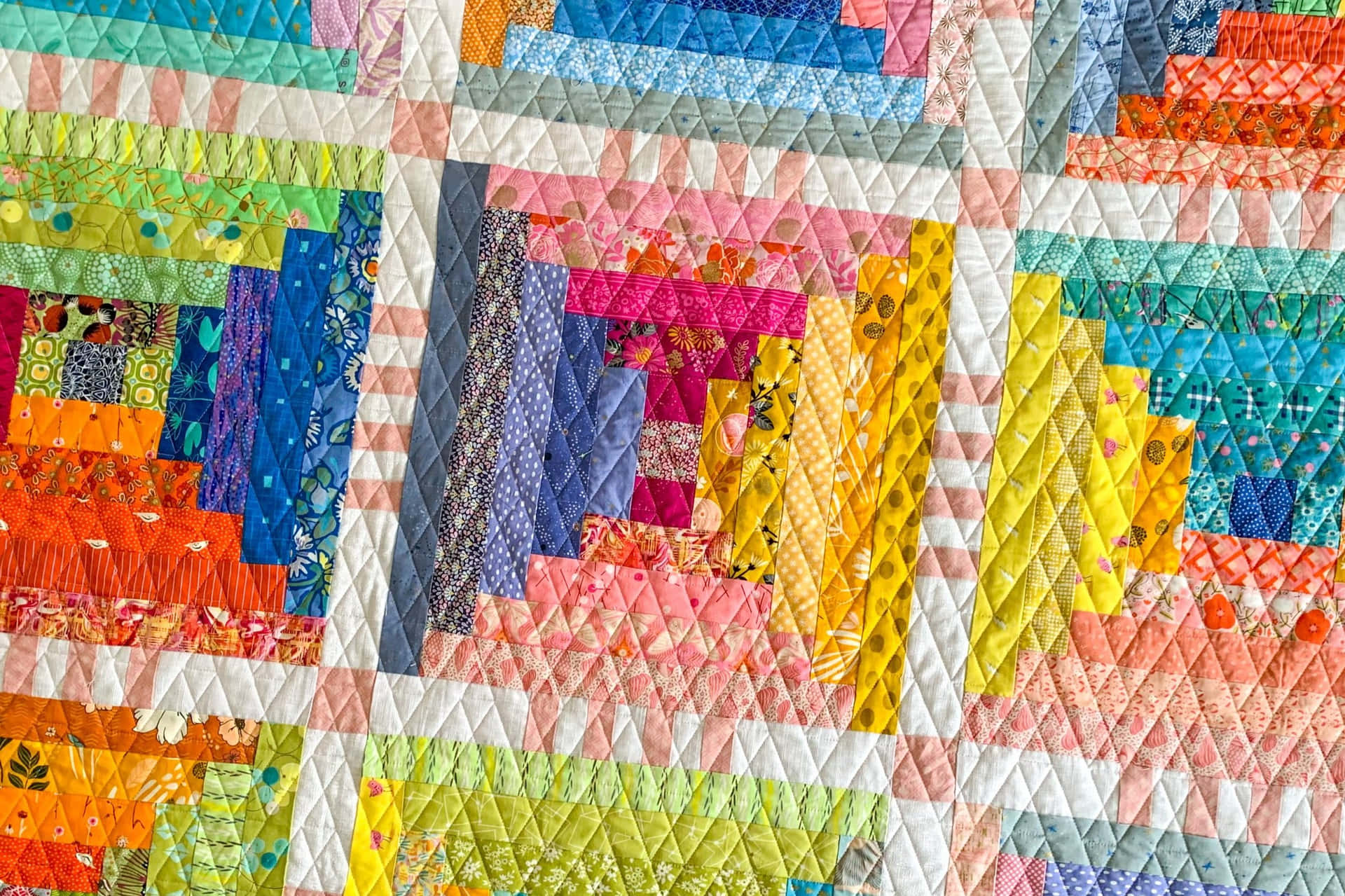 En farverig quilt med blokke lavet af forskellige farver Wallpaper