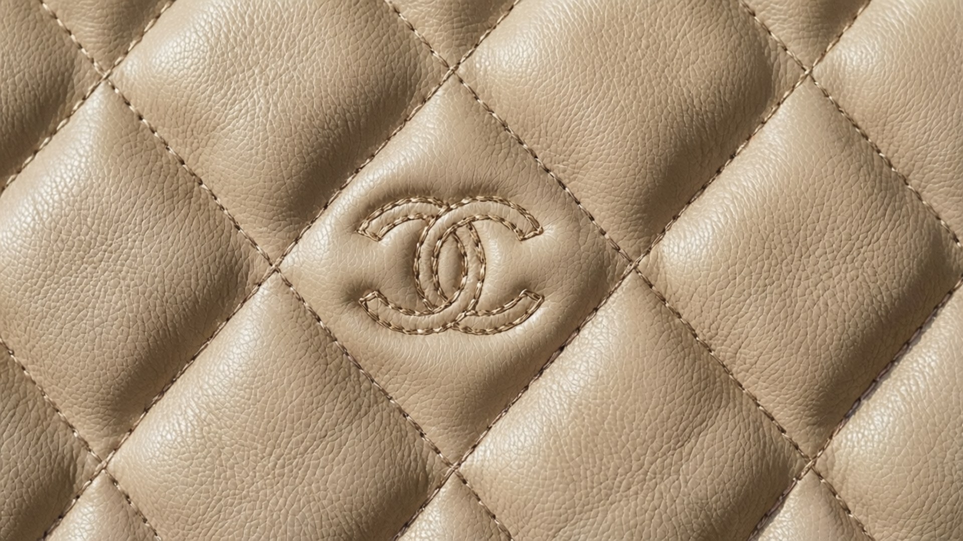 Quilted Pattern Taustakuvat — Lähikuva beigestä tikattua nahkaa, jossa ommeltu Chanel-logo keskitettynä timanttikuvioon.