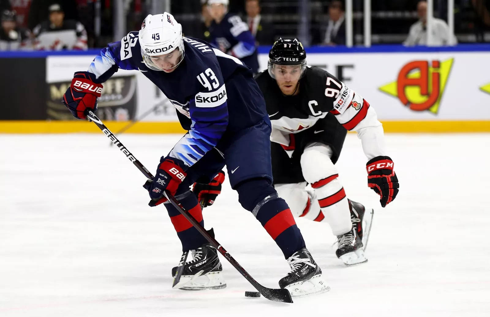 Quinn Hughes Dribbling Hockey Puck In Front Of Player From Team Canada Wallpaper