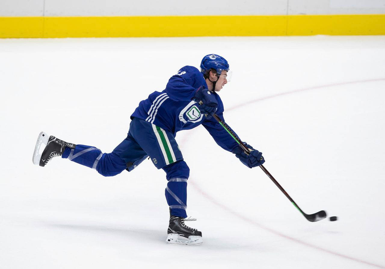 Quinn Hughes Dribbling Hockey Puck With Left Leg Raised During Game Wallpaper