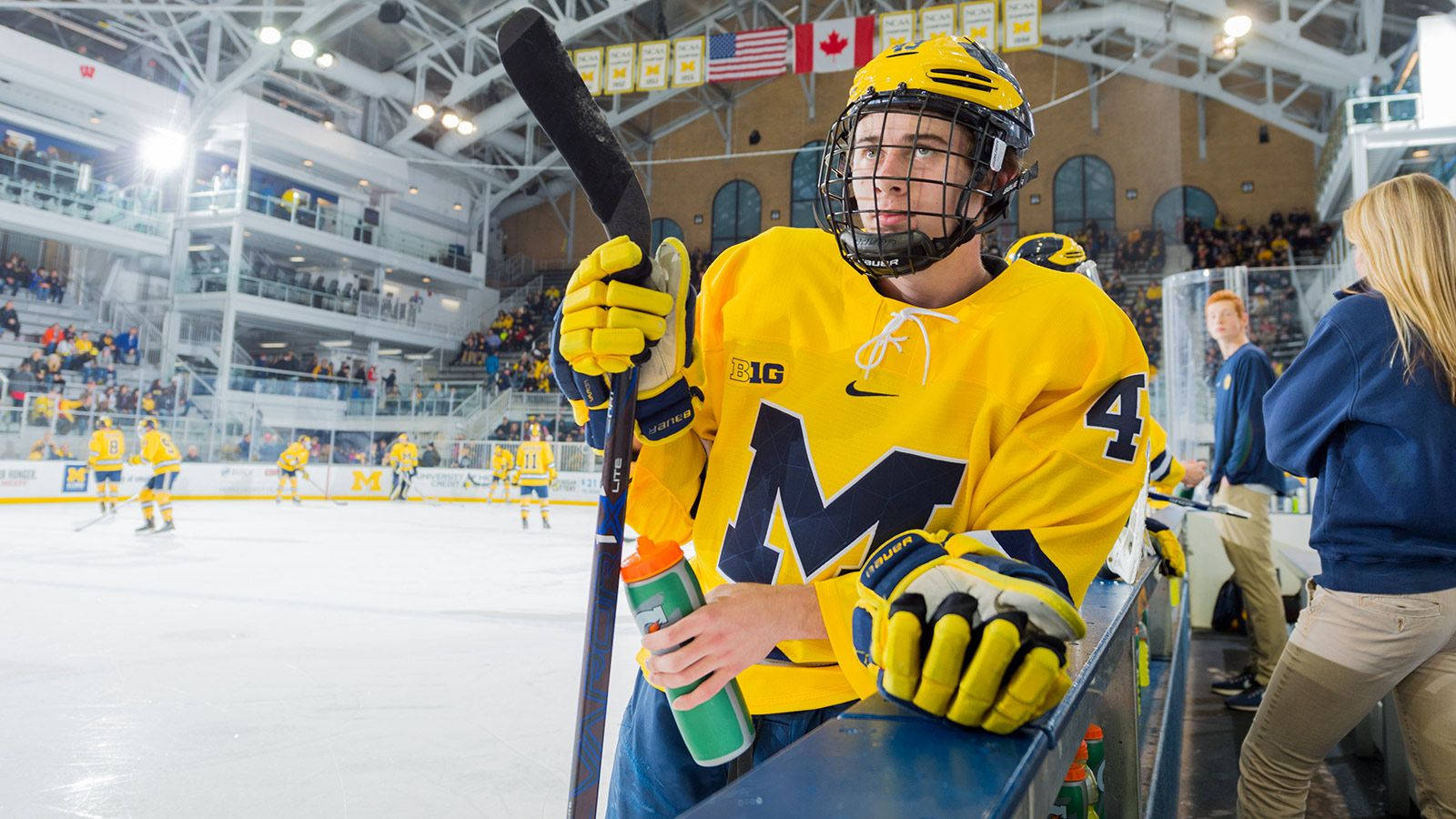 Quinn Hughes Resting During Warm-up Holding Tumbler And Hockey Stick Wallpaper
