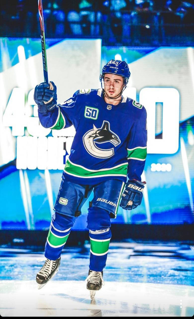 Quinn Hughes Straight Face While Holding Hockey Stick In The Air Wallpaper