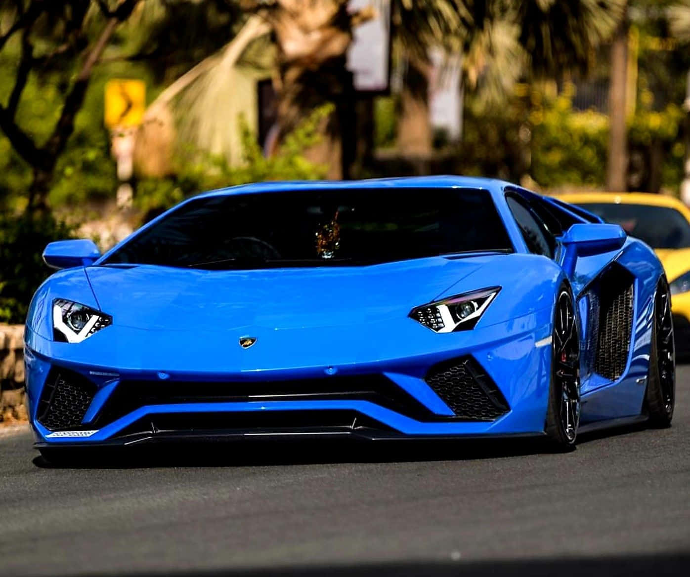 A Blue Sports Car Driving Down A Street