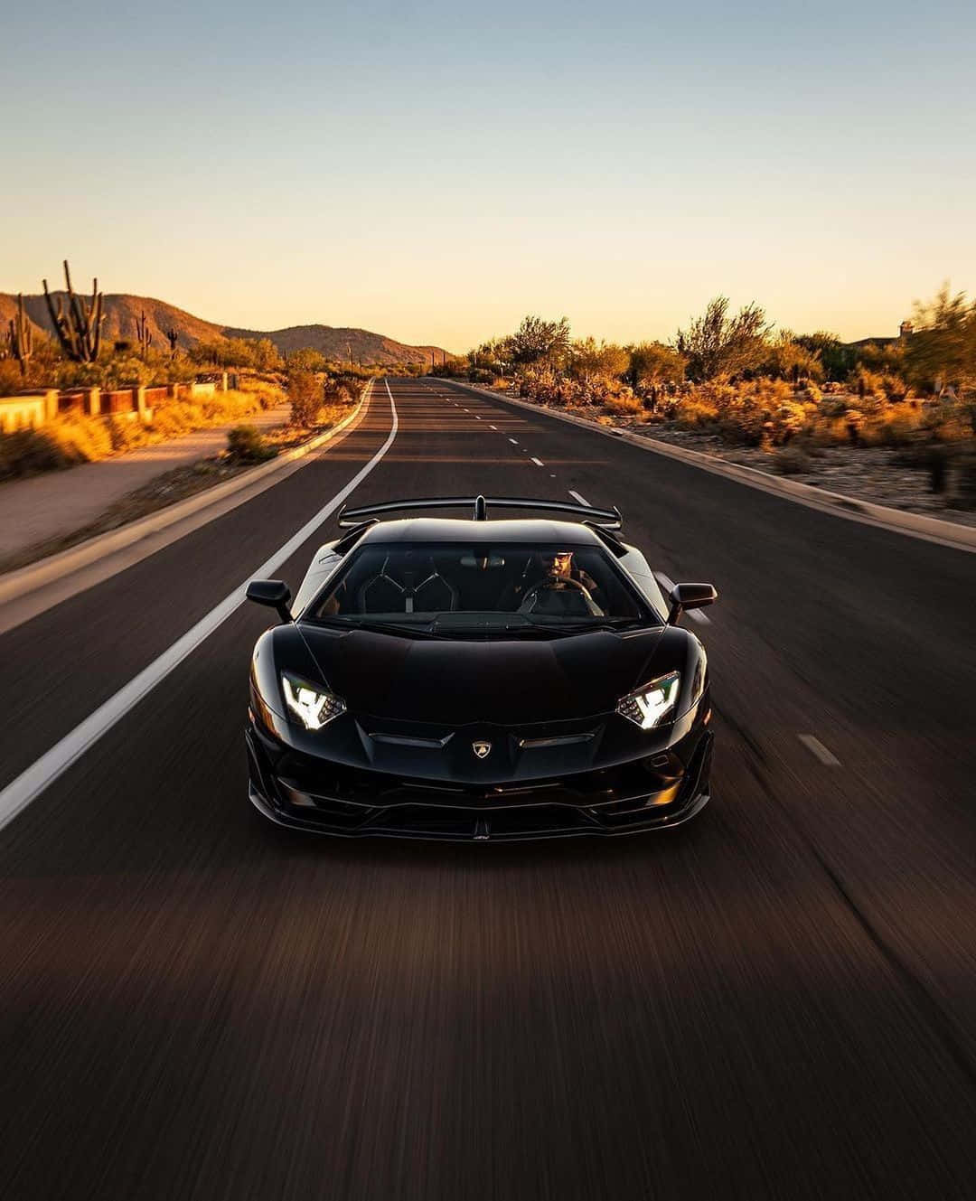 A Black Sports Car Driving Down A Desert Road