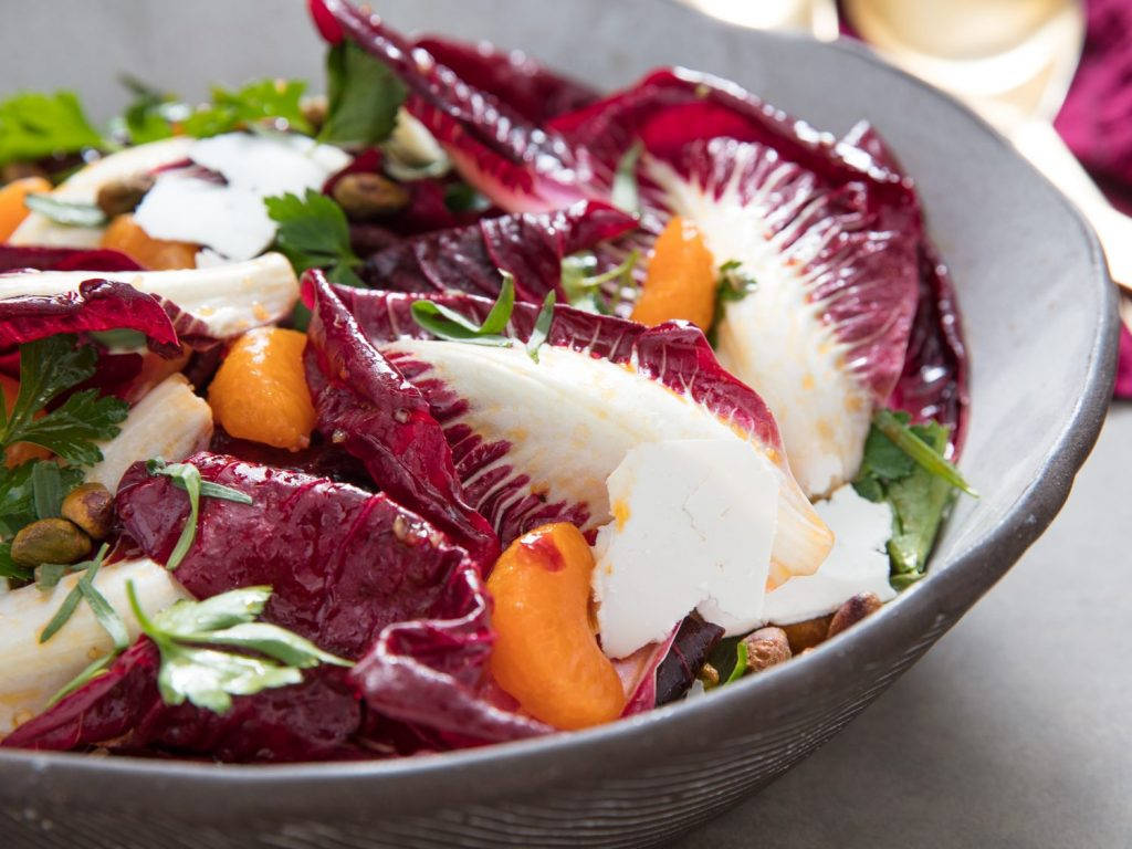 A vibrant bowl of radicchio salad with satsumas, pistachios and a drizzle of vinaigrette Wallpaper