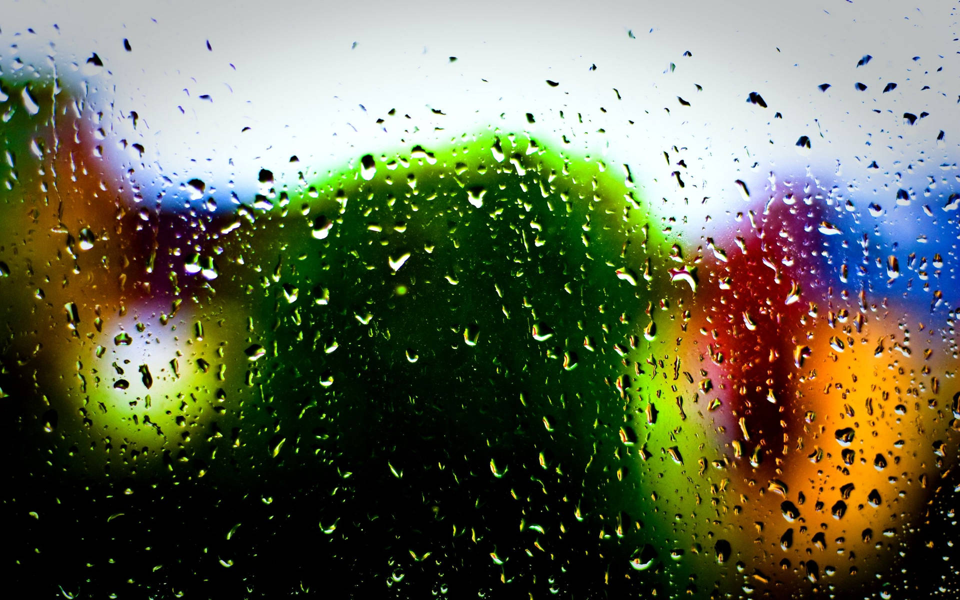 Gotasde Lluvia En La Superficie De Vidrio Con Efecto Bokeh Multicolor. Fondo de pantalla