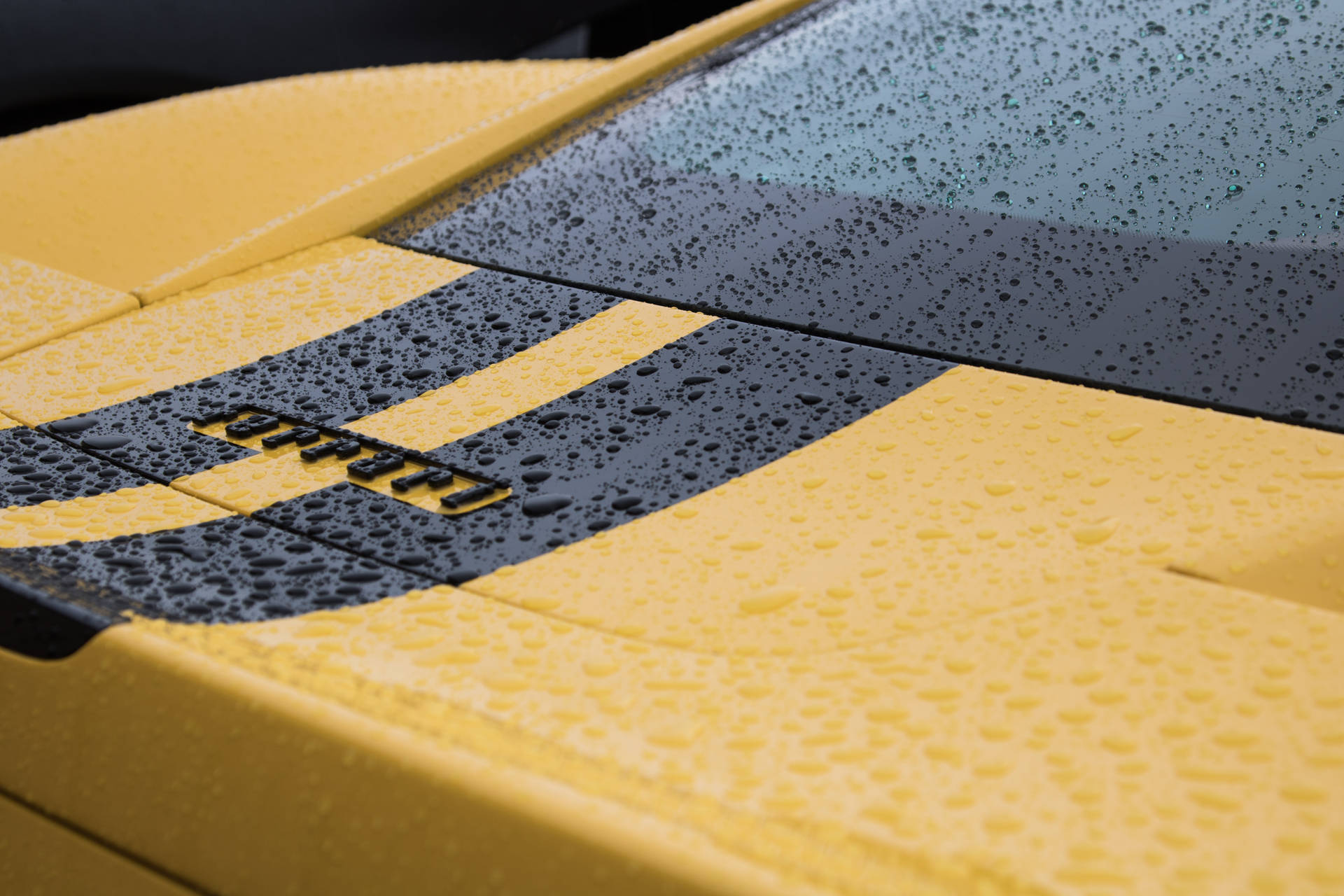 Raindrops on yellow Ferrari sports car surface wallpaper.
