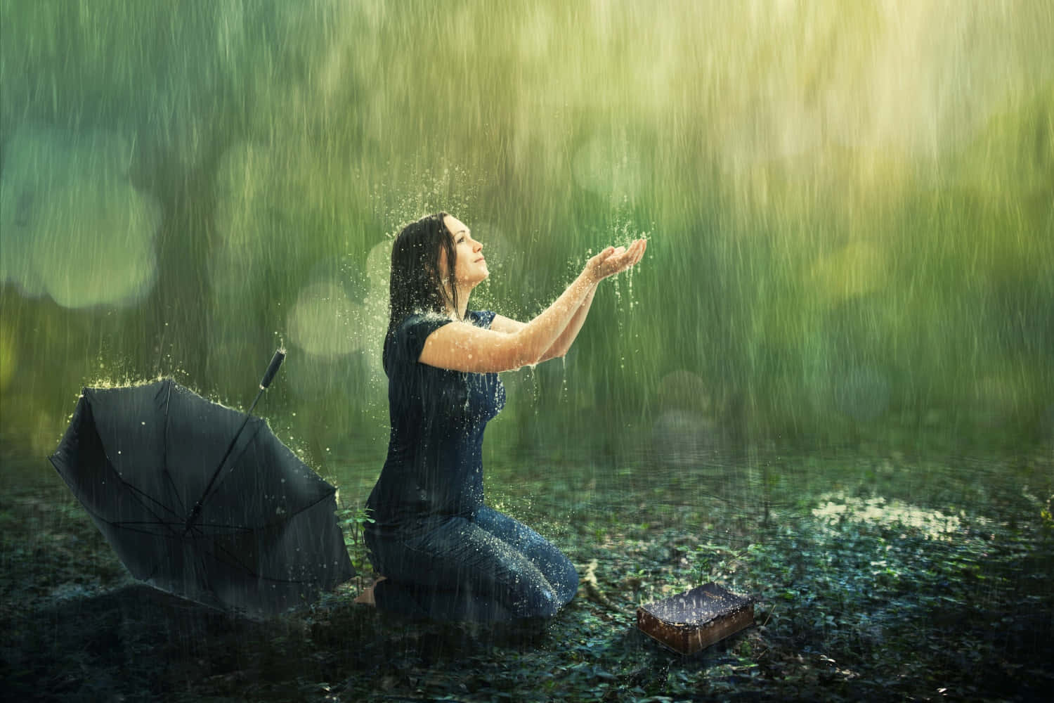 A Woman Kneeling Down In The Rain With An Umbrella