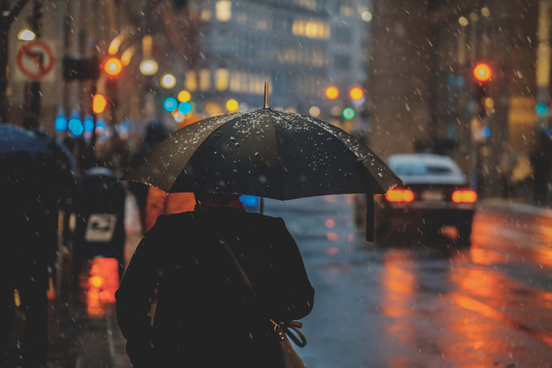 Mannmit Regenschirm Vor Städtischen Lichtern An Einem Regnerischen Tag Bild