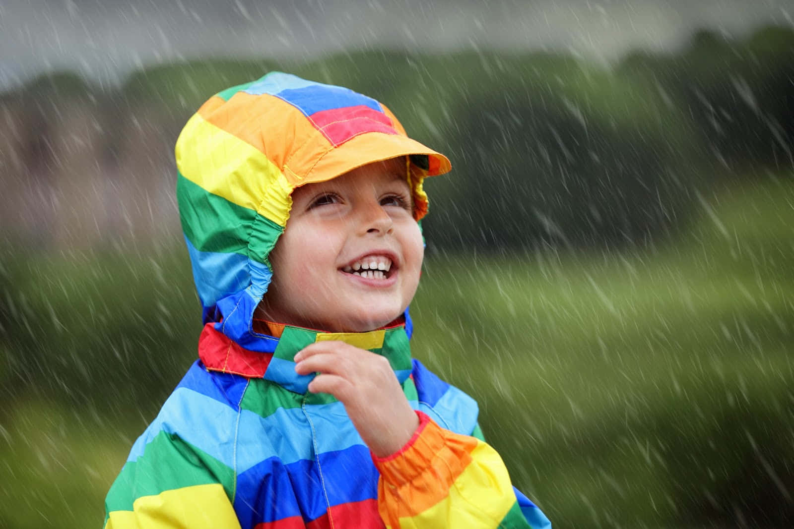 Billedeaf Et Barn Iført En Farverig Frakke På En Regnvejrsdag.