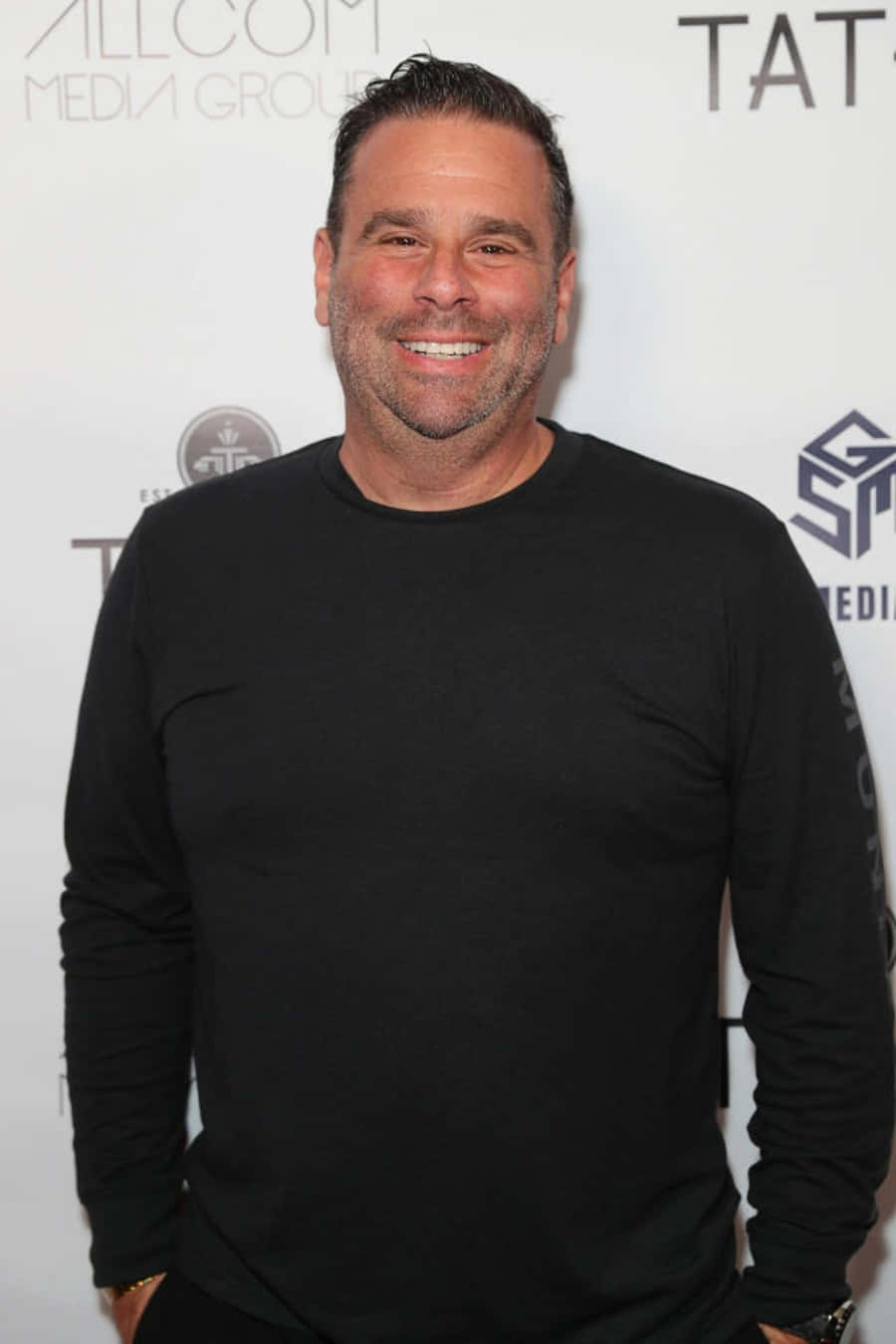 A Man In Black Shirt Smiling On The Red Carpet