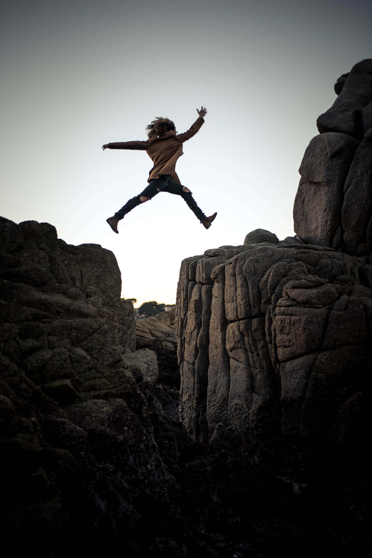 Energetic Leap on a Rocky Cliff Wallpaper