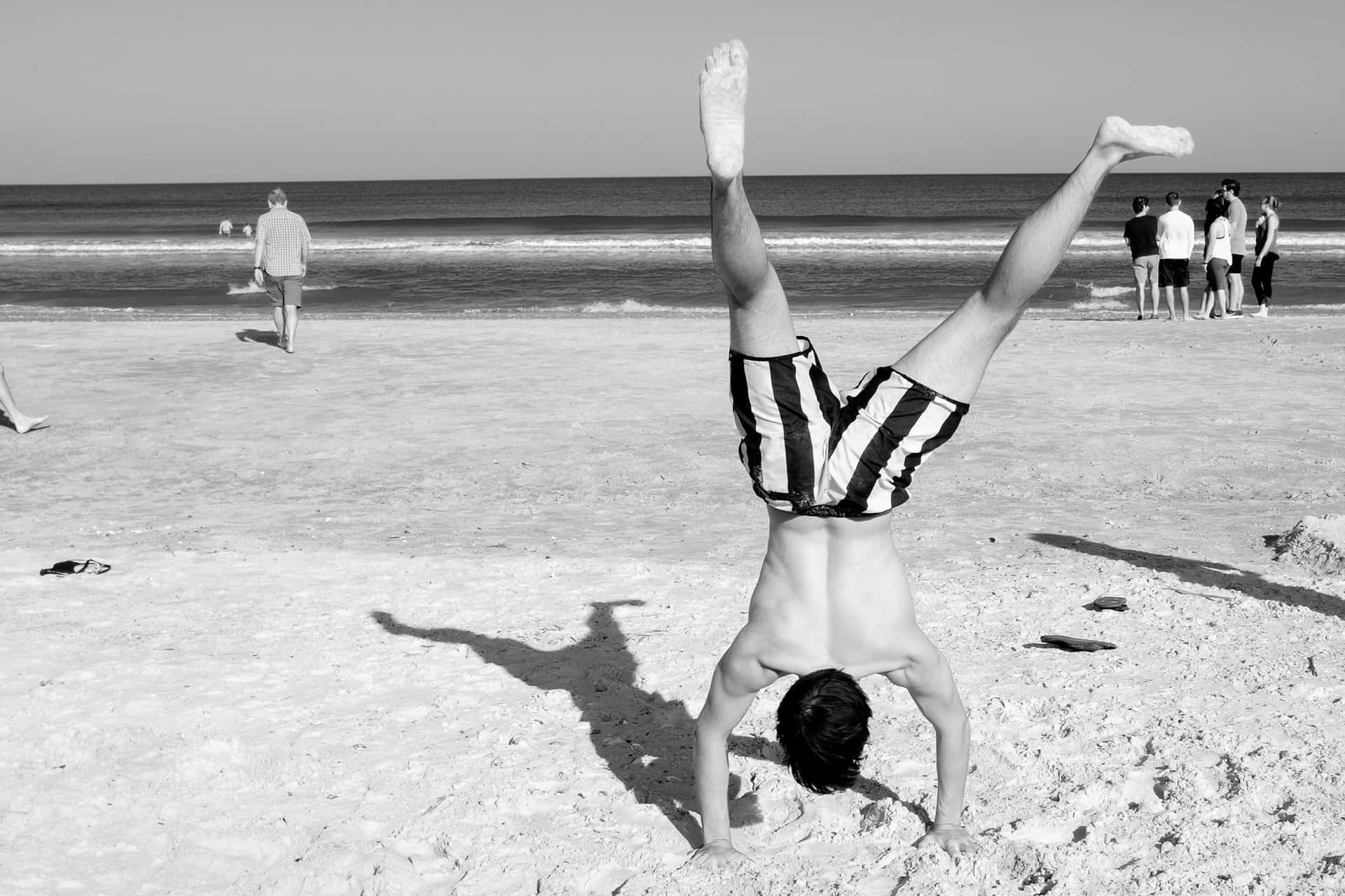 Random Person Performing Handstand On Beach Wallpaper