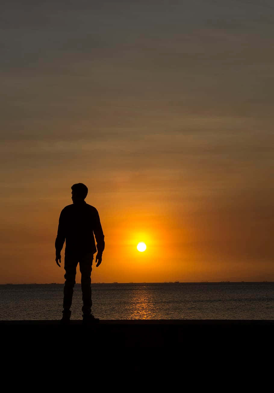 En vilkårlig person, der ser solnedgangen over havet Wallpaper