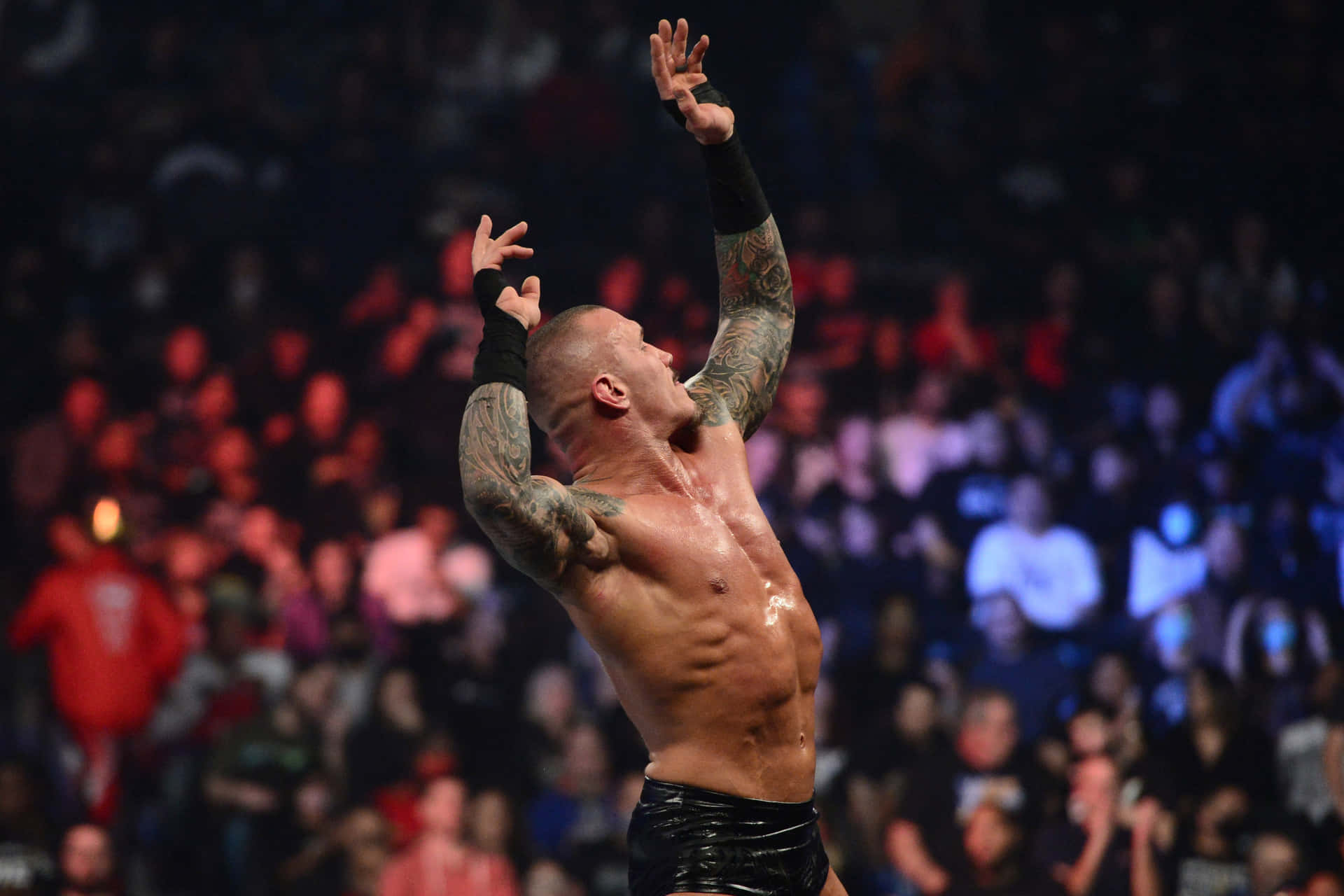 A Wrestler With Tattoos Is Holding His Arms Up In The Air Wallpaper
