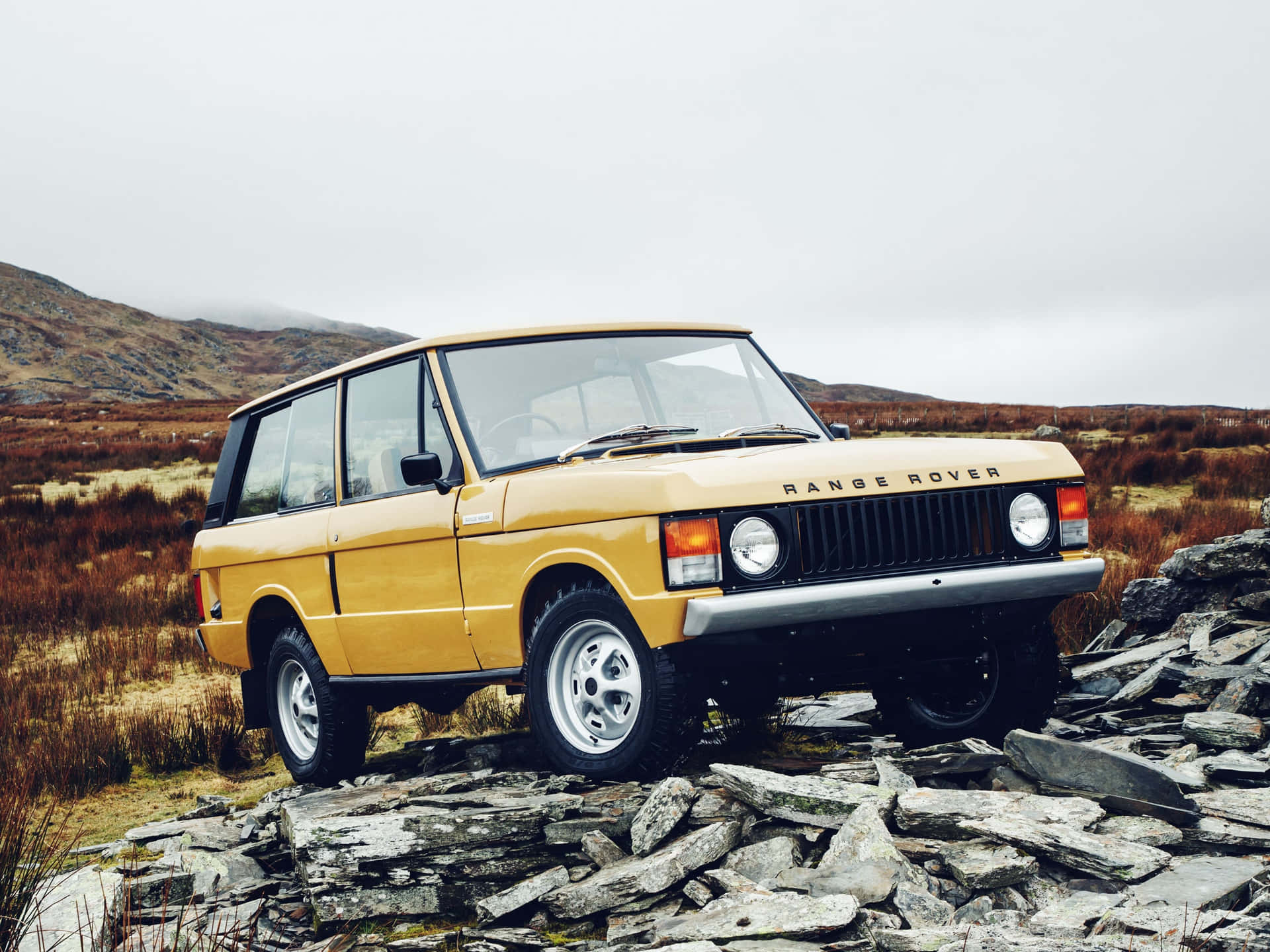 A Yellow Land Rover Parked On Rocks