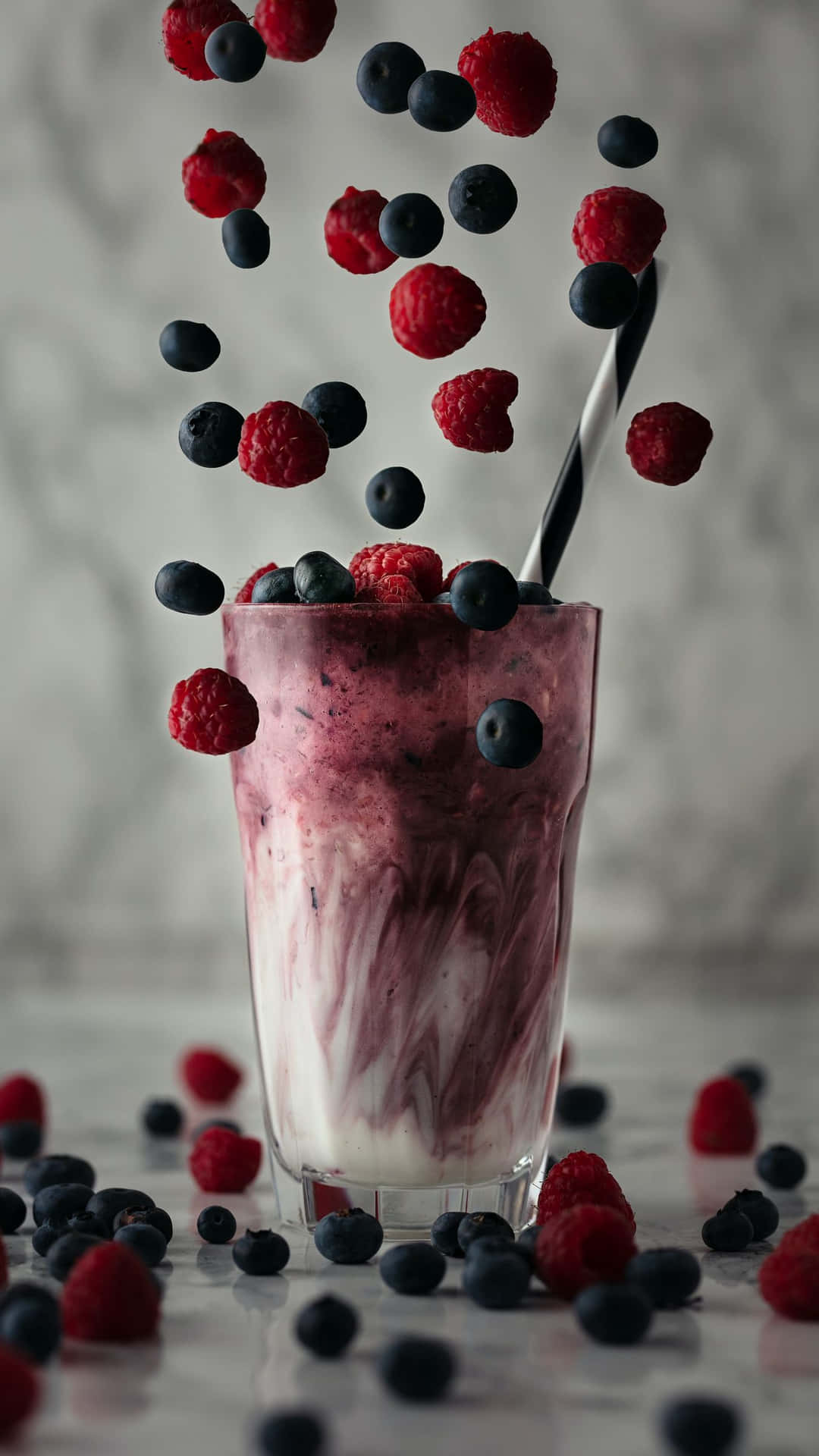 A Cup Of Yogurt With Berries Falling From It