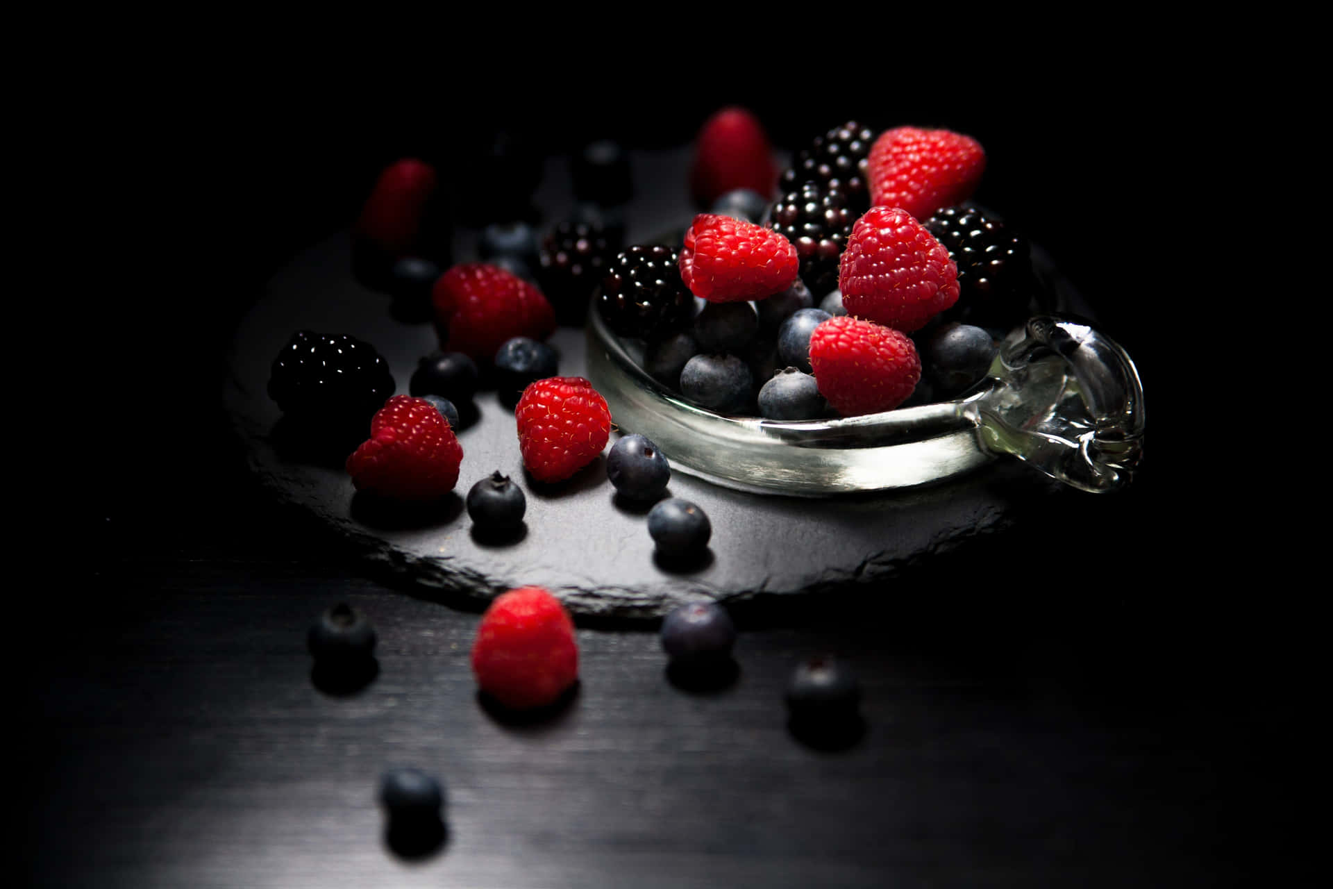 A Glass Bowl Of Berries On A Black Background