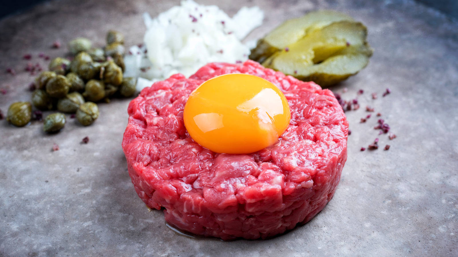 A Close-Up View of Gourmet Steak Tartare Topped With Spicy Sauce and a Fresh Raw Egg Yolk Wallpaper