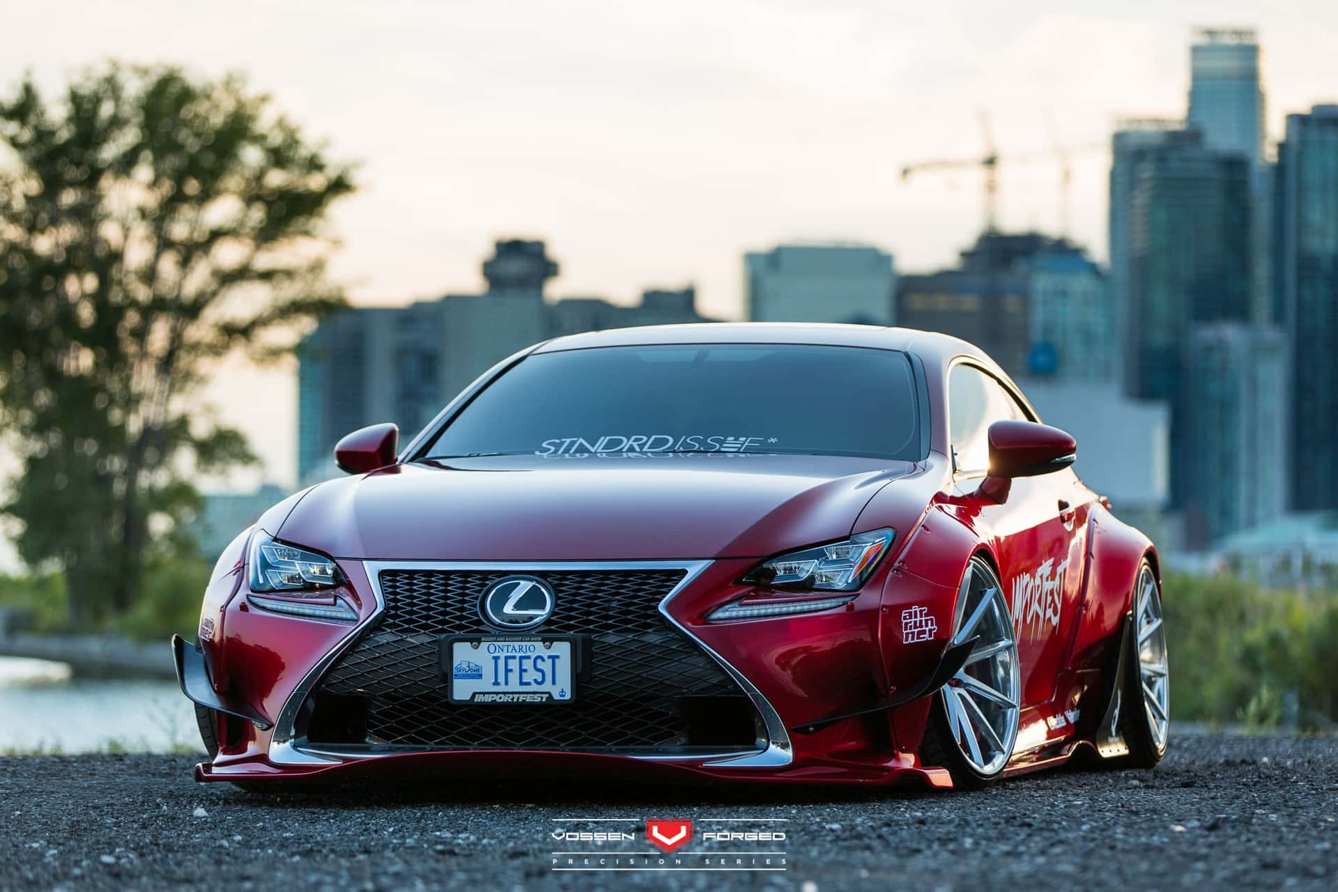 A Red Lexus Rc F Sport Parked In Front Of A City Wallpaper