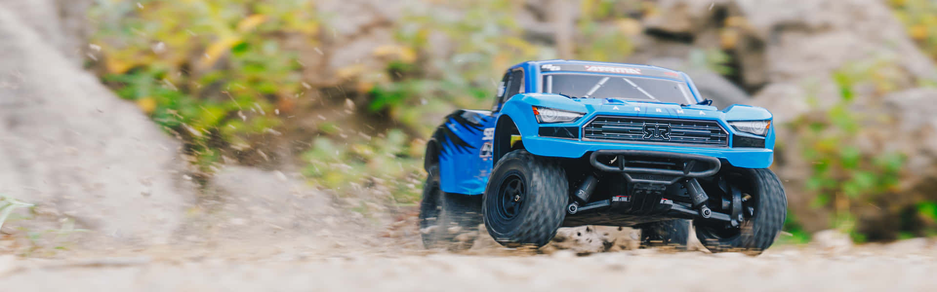 A Blue Toy Truck Is Driving Down A Dirt Road