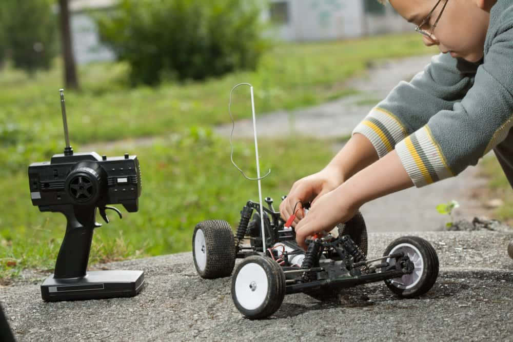 A Boy Is Working On A Remote Control Car