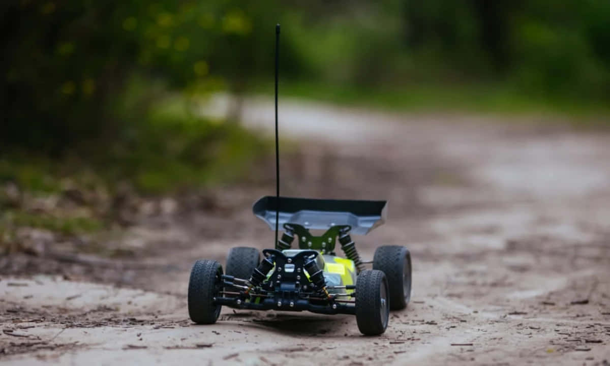 A Small Toy Car Is Driving Down A Dirt Road