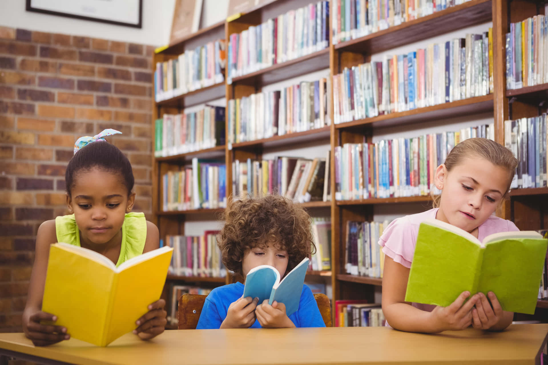 Three Children Reading Books In A Library