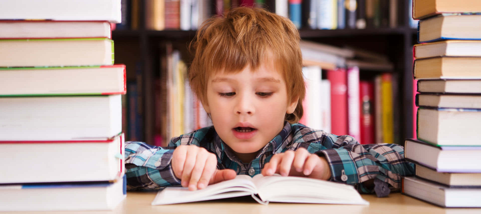 Einjunger Junge Liest Vor Einem Stapel Von Büchern Ein Buch.